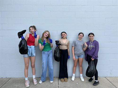5 girls collecting trash around campus